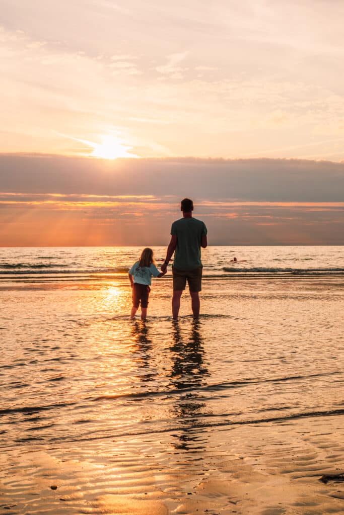 Vater und Kind in der Brandung am Strand von Zandvoort bei Sonnenuntergang