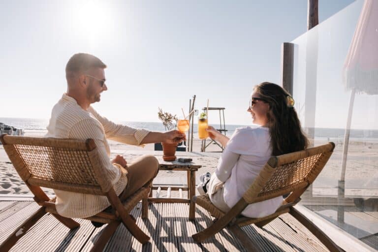 ein Mann und eine Frau sitzen an einem Tisch mit Getränken am strand Zandvoort